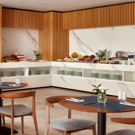 NH_Luz_Huelva_Buffet_Breakfast_Overview_Natural_Light_Food_Tables_Chairs_Flowers_Cutlary_Plates